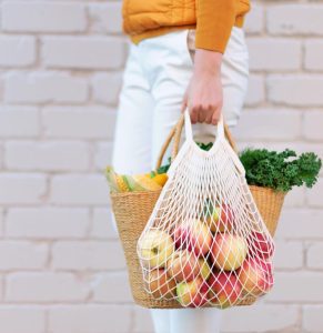 Woman grocery shopping with a bag of red apples